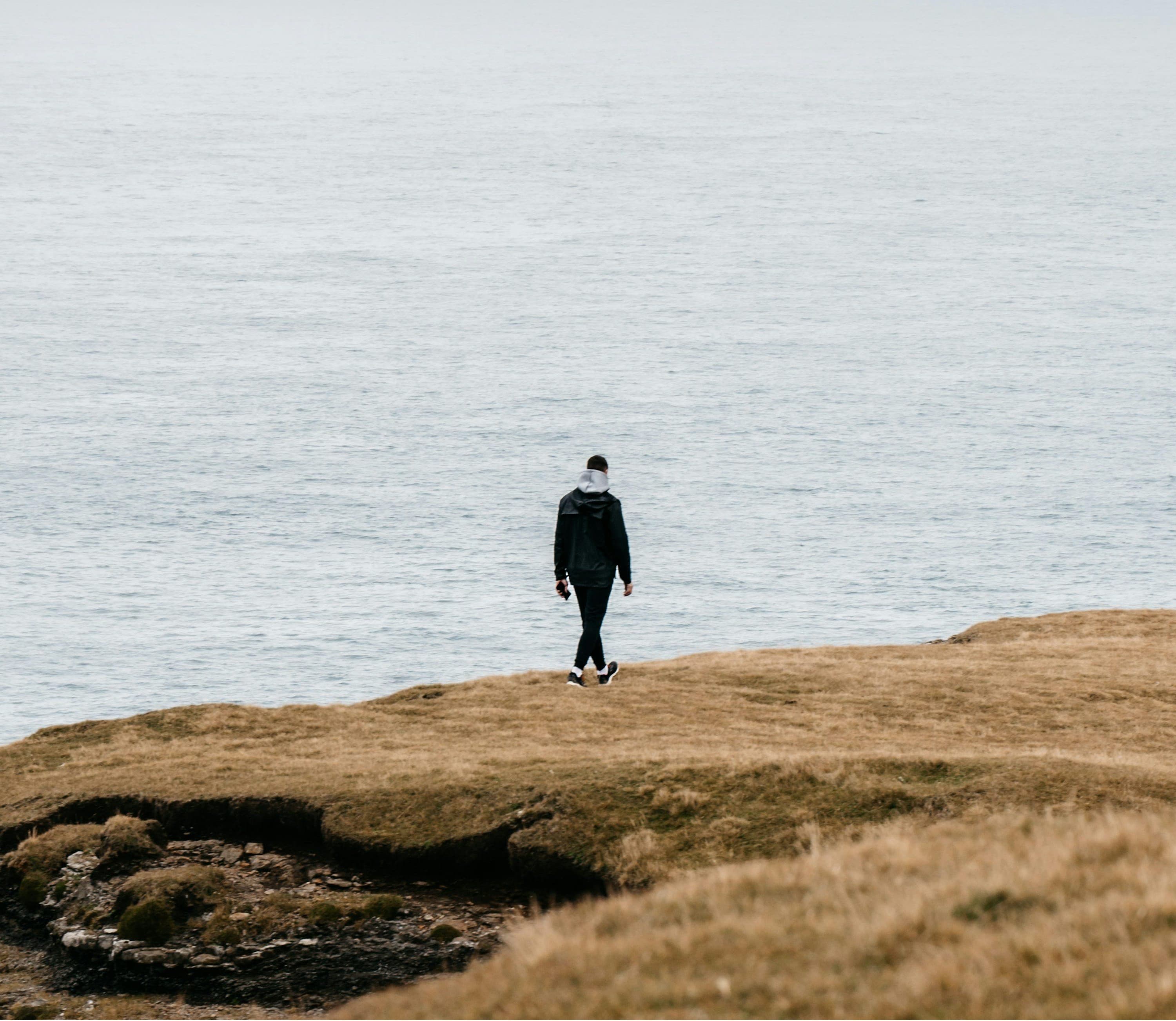 A solitary figure walking along a quiet shoreline